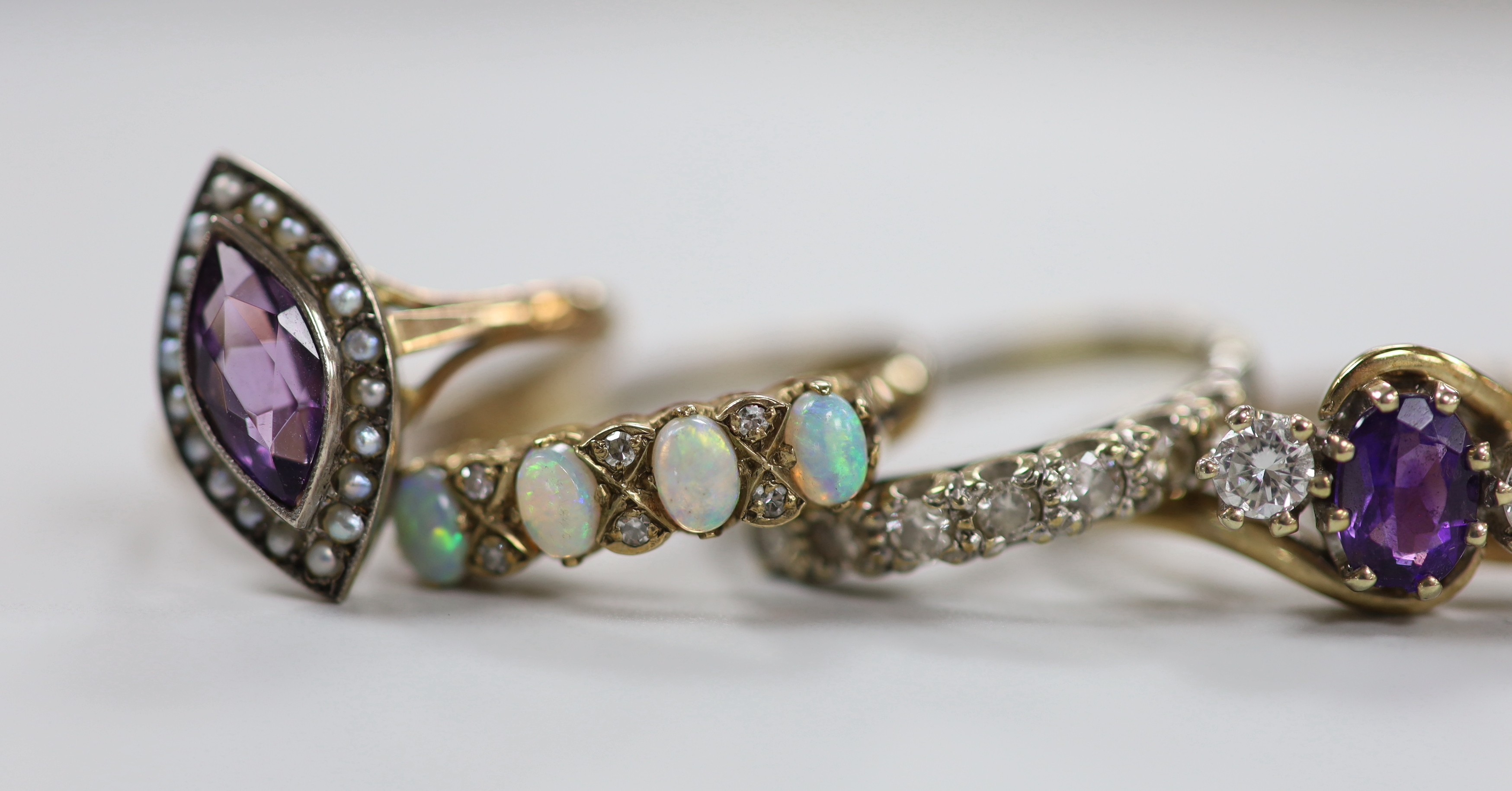 Six assorted modern 9ct and gem set rings, including an amethyst and diamond set three stone crossover ring, size R, white opal and diamond chip and a 9ct and 'sil', amethyst and seed pearl cluster ring, gross weight 15.